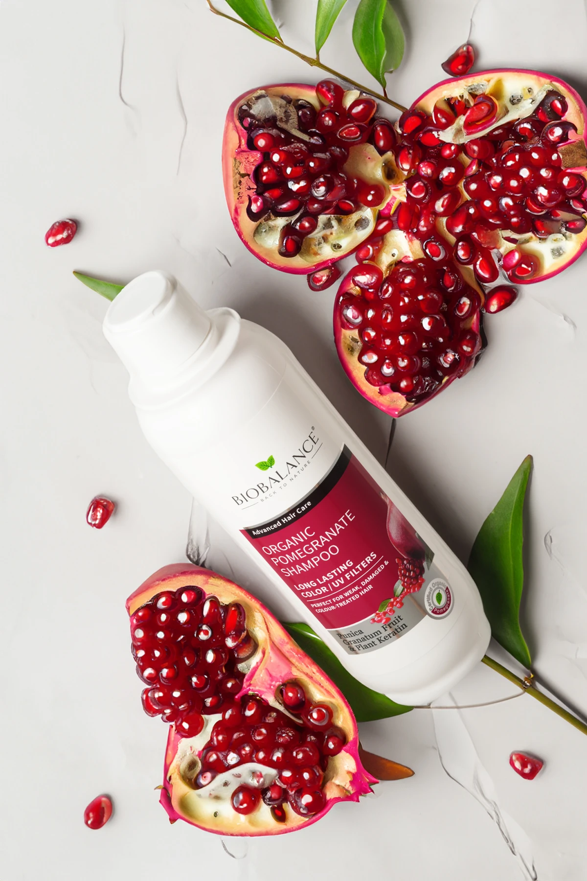 BioBalance Pomegranate Shampoo with pomegranate seeds and green leaves in the background