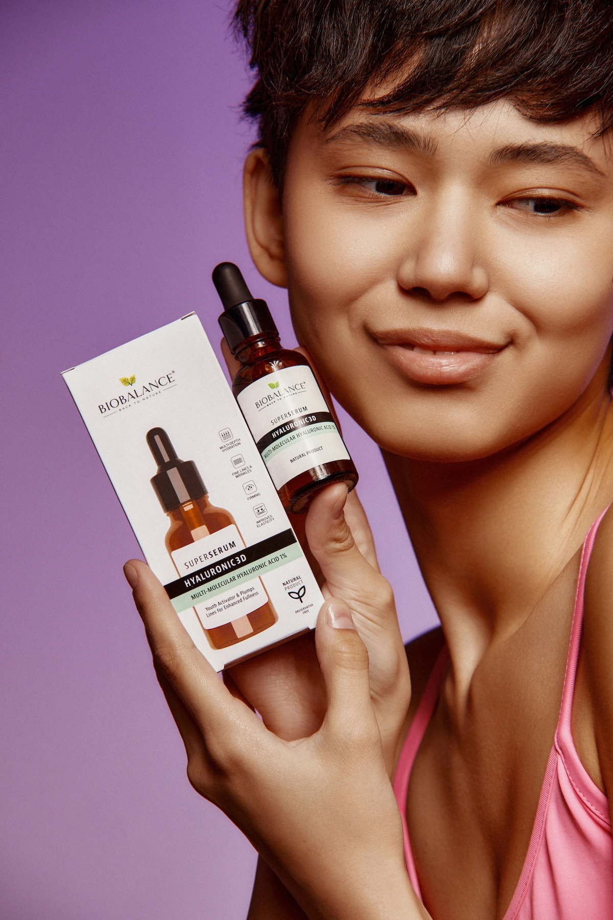 Girl gently holding BioBalance Hyaluronic 3D serum to her cheeks